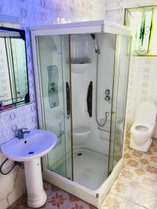 ein Bad mit einer Dusche, einem Waschbecken und einem WC in der Unterkunft New Mazubu Grand Hotel Mererani in Mbuguni