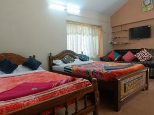 sypialnia z dwoma łóżkami i telewizorem na ścianie w obiekcie QUEENS COTTAGE - individual cottage w mieście Utakamand