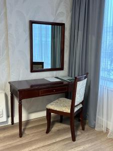 a wooden desk with a mirror and a chair at G Empire in Astana