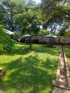 a park with tables and umbrellas in the grass at VICTORIA RIPPLE HOTEL { WINAM } in Kisumu