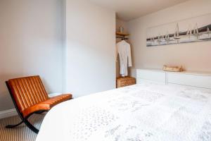 a bedroom with a white bed and a chair at Alba Cottage in Whitstable