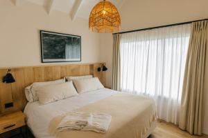 a bedroom with a bed and a window with a chandelier at La Galeria - Hotel Boutique Cariló in Carilo