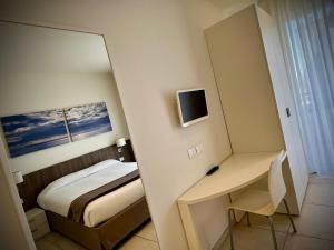 a bedroom with a bed and a desk and a mirror at Residenza Roma Marina in Sottomarina