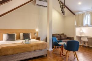 een slaapkamer met een bed en 2 stoelen en een bank bij Injoy Suítes & Aparts in Rio de Janeiro