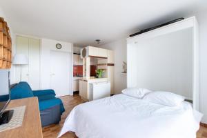 a bedroom with a white bed and a blue couch at Les dunes * parking privé * piscine * Aperçue mer in La Grande-Motte