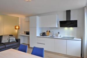 uma cozinha com armários brancos e cadeiras azuis numa sala de estar em Ferienwohnung in Limone Sul Garda mit Garten und Terrasse und Seeblick em Limone sul Garda