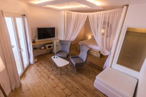 a bedroom with a bed and two chairs and a tv at SALT SUITES MILOS in Pollonia