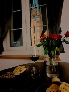 a table with a glass of wine and a vase of flowers at Apartament Nova in Racibórz