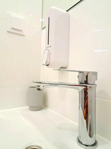 a chrome sink in a white bathroom with at Apartament Nova in Racibórz