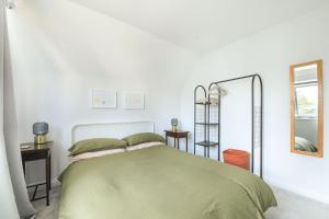 a white bedroom with a bed and a mirror at Cedar House in Whitstable
