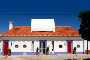un edificio blanco con techo rojo y una valla publicitaria. en Altinho B&B - Quartos - Rooms - Odeceixe, en Odeceixe