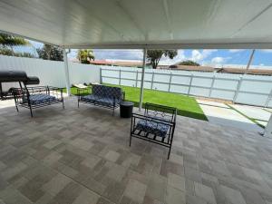 Stadium Chic Oasis: Modern Retreat in Miami close to Beaches في ميامي غاردنز: فناء بأربعة كراسي وطاولة وخيمة