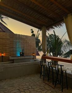 a patio with chairs and a table and a counter at Beach house steps from the sea in Ban Bang Po