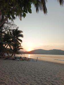 a sunset on a beach with chairs and palm trees at 8 Star Paradise in Locaroc