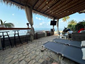 a room with a couch and a bar and the ocean at Beach house steps from the sea in Ban Bang Po