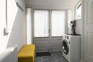 eine Waschküche mit einer Waschmaschine und einem gelben Stuhl in der Unterkunft Nythfa in Llanrwst