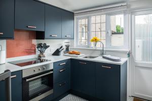 eine Küche mit blauen Schränken, einem Waschbecken und einem Fenster in der Unterkunft Nythfa in Llanrwst