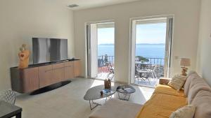 a living room with a couch and a television and a balcony at Grand Hotel - Appartement in Sainte-Maxime