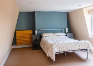 ein Schlafzimmer mit einem Bett, einer Kommode und einer blauen Wand in der Unterkunft Large Central 5 Bed House with Stunning Gardens! in Cheltenham