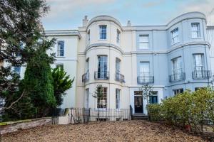 a large white house with a fence in front of it at Large Central 5 Bed House with Stunning Gardens! in Cheltenham