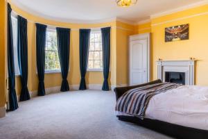 a bedroom with yellow walls and blue curtains and a bed at Large Central 5 Bed House with Stunning Gardens! in Cheltenham