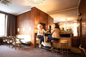 two women sitting at a bar in a restaurant at Select Hotel Prinz Eugen Wien in Vienna