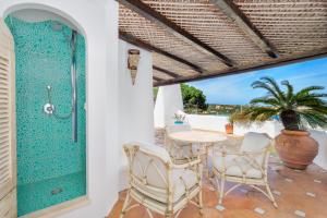 eine Terrasse mit einem Tisch, Stühlen und einer Glastür in der Unterkunft Terrazza sul mare a Porto Cervo in Porto Cervo