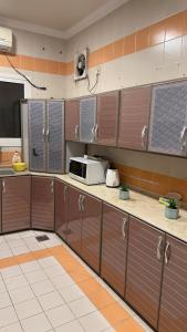 a kitchen with brown cabinets and a microwave on the counter at فيلا العزيزيه - الخبر in Al ‘Azīzīyah