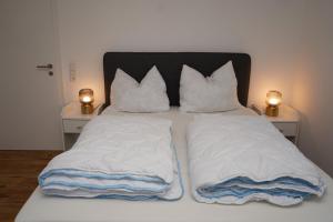 a bed with white sheets and pillows on it at Voßgarten Wohnung 1 in Duhnen