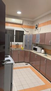 a large kitchen with brown cabinets and a white tile floor at فيلا العزيزيه - الخبر in Al ‘Azīzīyah