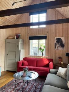 ein Wohnzimmer mit einem roten Sofa und einem Tisch in der Unterkunft Bo i egen stuga på härlig ölandsgård in Köpingsvik