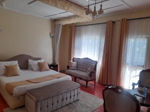 um quarto com uma cama, um sofá e uma cadeira em VICTORIA RIPPLE HOTEL { WINAM } em Kisumu