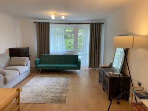 a living room with a green couch and a television at Spacious - 3 double beds - Wi-Fi - Central Northwood - Free Parking in Northwood