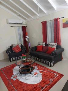 a living room with two black couches and a red rug at Royal Palm Luxury Villas in Ocho Rios