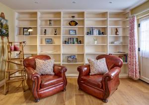 two leather chairs in a room with a book shelf at Rose Cottage - North Elmham in North Elmham