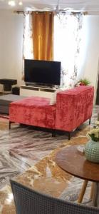Nana Adu Guest House في Koforidua: غرفة معيشة بها أريكة حمراء وتلفزيون