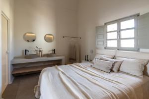 a white bedroom with a bed and a sink at Frescoes Luxury Suites in Mesaria