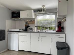 a kitchen with white cabinets and a sink and a window at Luxe chalet Friesland i14 - 5 pers in Westergeest