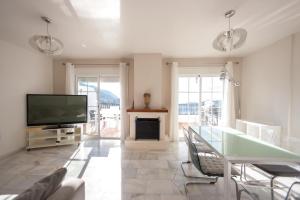 ein Wohnzimmer mit Fernseher und Tisch und Stühlen in der Unterkunft Villa Puerto Blanquillo in Frigiliana