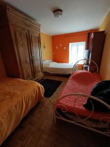a bedroom with two beds and an orange wall at Maison De Village in Barbechat