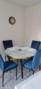 a table with blue chairs and a clock on the wall at Charmant Cachet in Sedan
