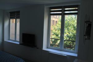 a room with two windows with a television in it at Charmant Cachet in Sedan