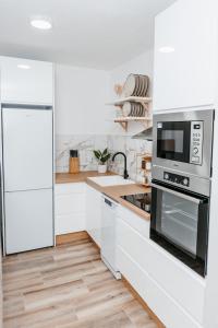 uma cozinha branca com um micro-ondas e um lavatório em Apartman FRIDAY em Travnik