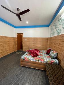 a bedroom with a bed and a ceiling fan at Chojh Inn Guest House in Kasol