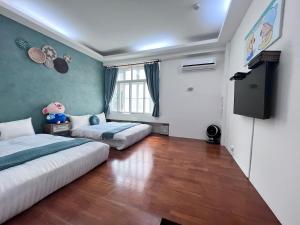 a bedroom with two beds and a flat screen tv at 墾丁PigHouse 豬窩親子包棟B館 in Hengchun