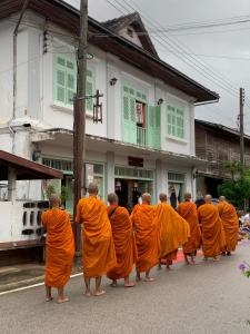 a group of monks in orange robes walking down a street at The White House in Chiang Khan