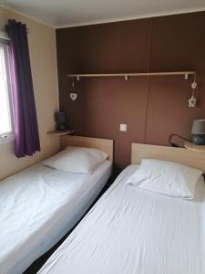 dwa łóżka siedzące obok siebie w pokoju w obiekcie MOBILHOME COSY SPACIEUX 42m2, CLIMATISE, TV & LL, 3 chambres w mieście Vic-la-Gardiole