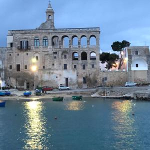 a large stone building with boats in a body of water at Prospettiva Polignano in Polignano a Mare