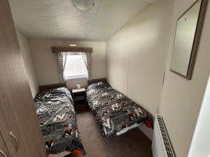 Cottamにある28 Trent viewのベッド2台と窓が備わる小さな客室です。