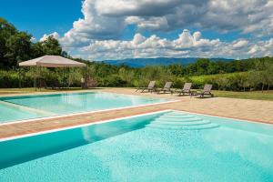 einen Pool mit Stühlen und einem Sonnenschirm in der Unterkunft Il Ciliegio - I Borghi Della Selvaccia in Cennina